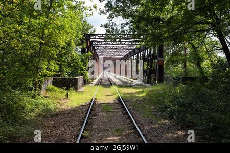 Ancienne ligne de chemin de fer traversant un pont rouillé transformé en voie de plaisance pour le train-cycle draisine avec quatre roues. Banque D'Images