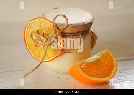 Bougie parfumée aromatique et orange sur fond blanc rustique en bois ancien. Banque D'Images