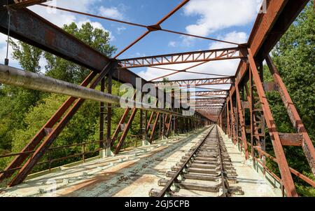 Ancienne ligne de chemin de fer traversant un pont rouillé transformé en voie de plaisance pour le train-cycle draisine avec quatre roues. Banque D'Images