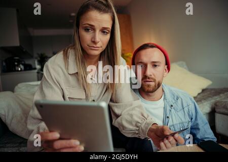 Couple caucasien assis sur un canapé regardant une tablette numérique pendant un appel vidéo Banque D'Images