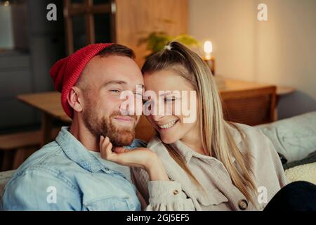 Gros plan romantique couple caucasien assis sur le canapé être affectueux Banque D'Images