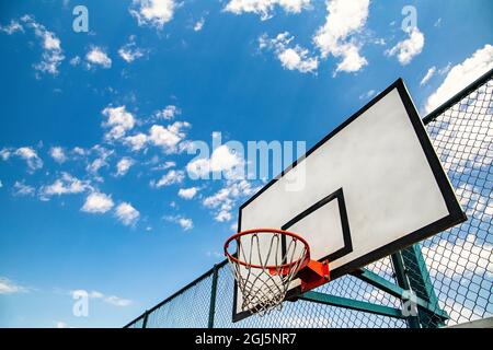 Panier de basket-ball extérieur avec espace de copie. Bleu ciel comme arrière-plan. Jeu de jeunes urbains. Banque D'Images