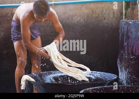 Des hommes travaillant et se dansant dans des bacs de lavage dans une usine de tissus à Mandalay, au Myanmar. Banque D'Images