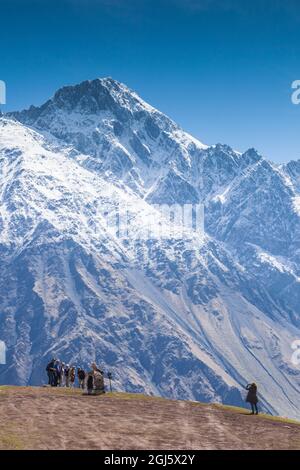 Géorgie, route militaire géorgienne, Kazbegi-Stepantsminda. Visiteurs à l'église de la Trinité de Gergeti par Mt. Kazbek. Banque D'Images