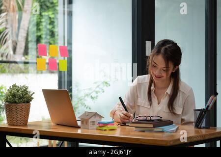 Photo d'une femme asiatique travaillant avec un ordinateur portable dans son bureau. Banque D'Images