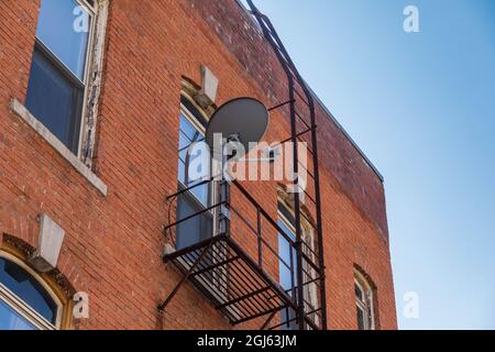 un feu s'échappe sur le côté d'un bâtiment et d'une parabole satellite Banque D'Images