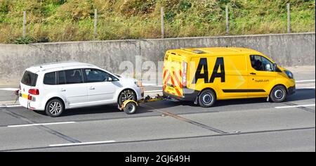 Voiture à hayon blanche VW cinq portes remorquée par une fourgonnette de transport jaune AA Ford et conducteur une entreprise de dépannage opérant au sein de la marque ARC Europe sur l'autoroute britannique Banque D'Images