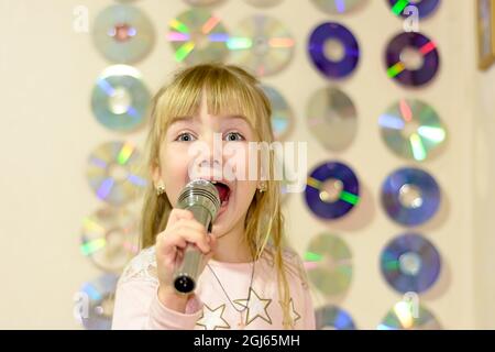 Une petite fille avec microphone chante des chansons Banque D'Images