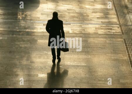 Silhouette de l'homme solitaire avec un sac marchant dans la rue. Banque D'Images