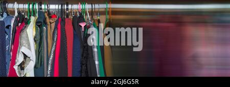 Bannière panoramique. Armoire avec vêtements suspendus sur des cintres de différentes couleurs. Des vêtements colorés accrochés au rail dans une armoire en bois Banque D'Images