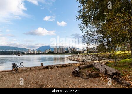 Femme se reposant contre une bûche avec son vélo, regardant sur l'eau à la ligne d'horizon de Vancouver Banque D'Images