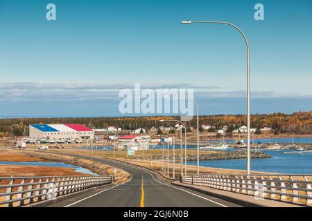 Canada, Nouveau-Brunswick, Île Miscou. Pont du port de Miscou avec vue sur les édifices du port aux couleurs acadiennes. Banque D'Images