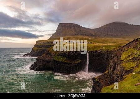 Europe, îles Féroé. Vue sur le village de Gasadalur et la cascade de Mulafossur sur l'île de Vagar. Banque D'Images