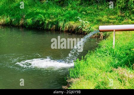 L'eau s'écoule à travers un tuyau dans le lac. Banque D'Images