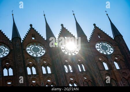 08 septembre 2021, Mecklembourg-Poméranie occidentale, Stralsund : le soleil brille à travers la façade gothique de l'hôtel de ville de Stralsund. La ville hanséatique de Stralsund, mentionnée pour la première fois en 1234, est l'un des aimants touristiques de Mecklembourg-Poméranie occidentale en raison de ses plus de 500 bâtiments classés, dont la plupart ont été largement restaurés ces dernières années avec l'aide de la Treuhänderische Sanierungsträger Stadterneuerungsgesellschaft Stralsund mbH (ses). La vieille ville médiévale de Stralsund, ainsi que la ville hanséatique de Wismar, ont été inscrites sur la liste du patrimoine mondial de l'UNESCO à Ju Banque D'Images