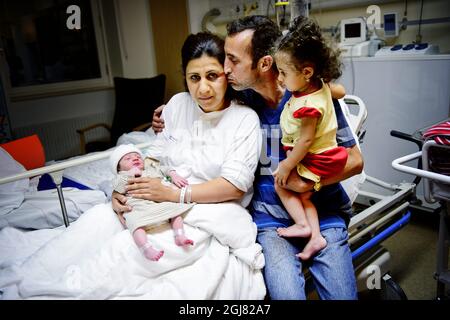GAVLE 2013-08-04 une femme a donné naissance à un enfant dans la voiture après un accident. Samahar Mezban et sa famille étaient lourdement enceintes et se sont alors mis en route vers la maternité de l'hôpital de Gavle, mais ils n'ont pas eu cette possibilité bien avant le moment. Le mari Mokhles Raheema a regardé sa femme et a vu que l'enfant était sur le chemin qui lui a fait perdre l'attention pendant une seconde, la voiture a frappé la bande médiane retourné et a fini dans un fossé. La famille s'est échappée sans préjudice et pendant le drame Samahar a donné naissance à une fille. Sur la photo: Mère Samaher Mezban à l'hôpital de Gavle avec la fille du nouveau-né, le mari Mokhle Banque D'Images