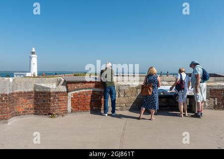 Les visiteurs du château de Hurst lisent un panneau d'information surplombant le phare de Hurst point sur le Solent dans le Hampshire, en Angleterre, au Royaume-Uni Banque D'Images