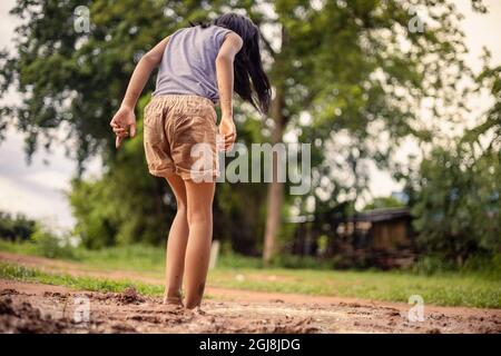 Une petite fille asiatique joue avec la terre dans la nature à sa maison pendant la journée. Banque D'Images