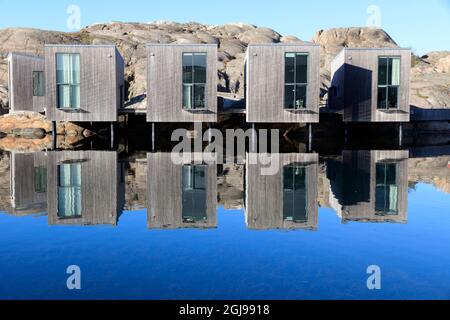 Suède, Bohuslan. Réflexions de condos contre le ciel bleu et le lagon d'eau de mer. (Usage éditorial uniquement) Banque D'Images