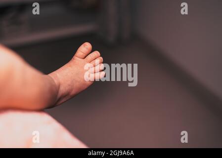 Gros plan de pied de bébé mignon méconnu tout en étant allongé dans le lit, concept d'innocence Banque D'Images