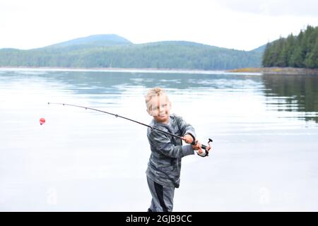 Alaska, Ketchikan, garçon de 5 ans qui se jette dans l'océan avec un poteau de pêche. (M.) Banque D'Images