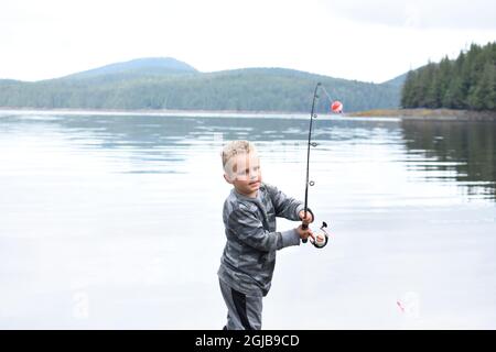 Alaska, Ketchikan, garçon de 5 ans qui se jette dans l'océan avec un poteau de pêche. (M.) Banque D'Images