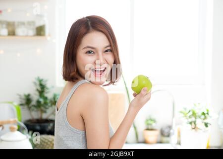 Happy Young Asian Woman Eating Apple vert sur la cuisine. Régime alimentaire. Concept de suivre un régime. L'alimentation saine Banque D'Images