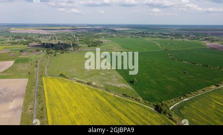 Champs de ferme colorés autour d'un petit village, vue aérienne. Banque D'Images