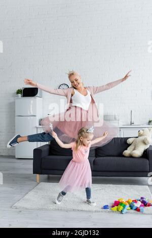 femme excitée avec fille dansant à la maison tout en portant des costumes de princesses Banque D'Images