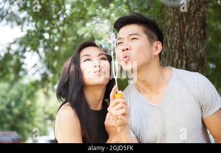 Un jeune couple d'Américains vietnamiens soufflait de bulles dans le parc en Floride (MR). Banque D'Images