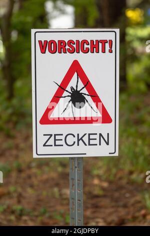 Gros plan d'un panneau d'avertissement dans une forêt avec inscription allemande de 'attention! Tiques Banque D'Images