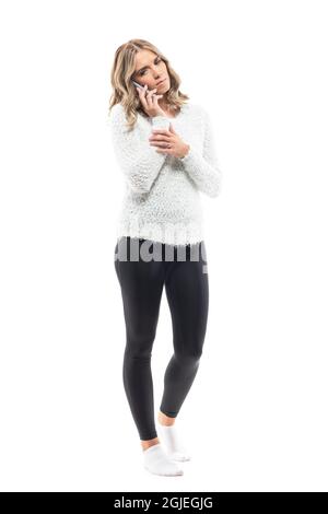 J'avais peur que la jeune femme, triste, parle au téléphone et regarde vers le bas. Portrait sur toute la longueur isolé sur fond blanc Banque D'Images