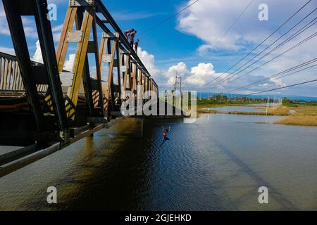 Des garçons ruraux sautant sur la rivière Hhoripur depuis le haut d'un pont pour s'amuser et s'amuser pendant la saison d'automne. Sylhet, Bangladesh. Banque D'Images