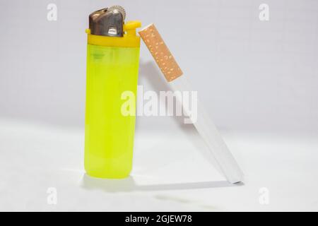 Un briquet jaune et une cigarette sur fond blanc. Banque D'Images