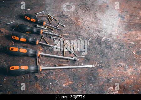 Tournevis et vis sur établi en bois. Vue de dessus des outils de travail avec espace pour le texte. Outils de construction sur table de travail en bois. Arrière-plan. Banque D'Images