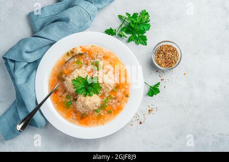 Soupe fraîche avec boulettes de viande et légumes verts frais sur fond gris. Banque D'Images