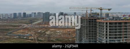 Grues de construction debout près de bâtiments inachevés à plusieurs étages Banque D'Images