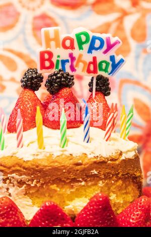 Gâteau d'anniversaire avec des bougies, fraises, mûres et un panneau disant Joyeux anniversaire. Banque D'Images