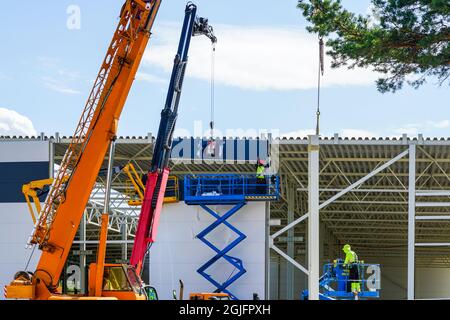 un mur à panneaux sandwich est monté à l'aide d'une grue télescopique et de ciseaux modernes Banque D'Images