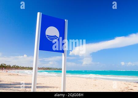 Bavaro, République Dominicaine - 15 janvier 2020: Paysage dominicain côtier avec bannière de plage Pavillon bleu par une journée ensoleillée Banque D'Images