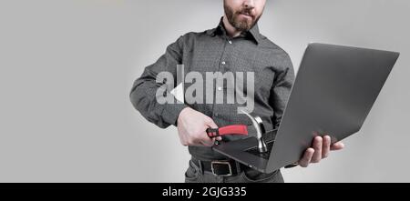 Homme non rasé coupe courte vue ordinateur portable frapper l'ordinateur avec fond gris marteau, dommages matériels Banque D'Images