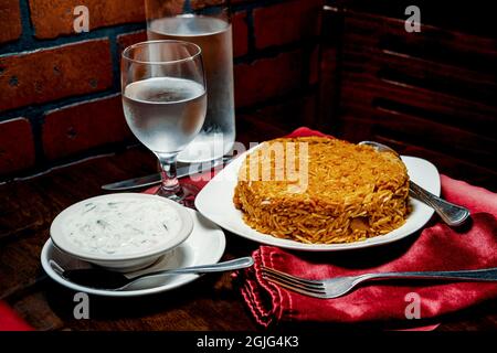 Riz biryani de poulet indien épicé à la raita fraîche Banque D'Images