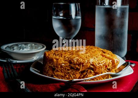 Riz biryani de poulet indien épicé à la raita fraîche Banque D'Images