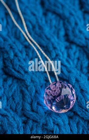 Grand cristal rose avec fil sur une table bleue tricotée. Banque D'Images