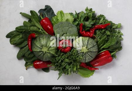 Légumes frais tels que courgettes, poivrons, brocoli et herbes - arugula, épinards et persil sur fond gris. Plats végétariens. Vue de dessus Banque D'Images