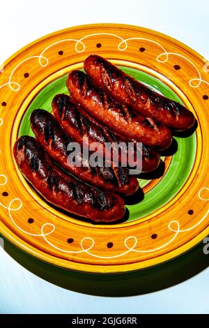 Cinq saucisses de kielbasa grillées sur une assiette colorée Banque D'Images