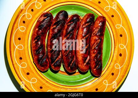 Cinq saucisses de kielbasa grillées sur une assiette colorée Banque D'Images