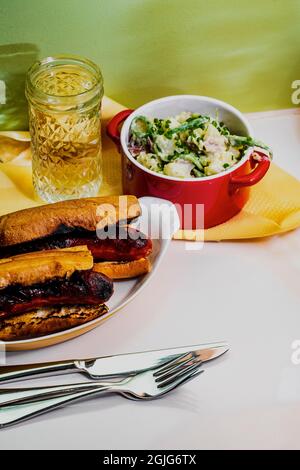 Sous-sandwich à la saucisse de kielbasa grillé au charbon de bois avec sauce à la déesse verte et salade de pommes de terre Banque D'Images