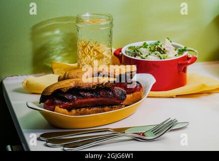 Sous-sandwich à la saucisse de kielbasa grillé au charbon de bois avec sauce à la déesse verte et salade de pommes de terre Banque D'Images