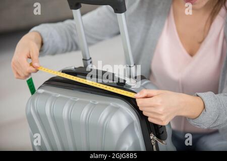 femme inspectant la mesure des bagages à main à l'aide d'un ruban de mesure Banque D'Images